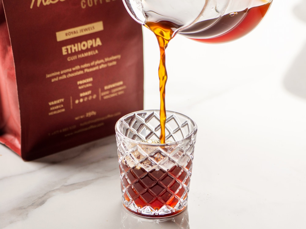 A person pours Ethiopian coffee into a glass.