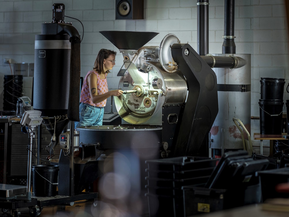 A woman roasts coffee using a Probat machine.