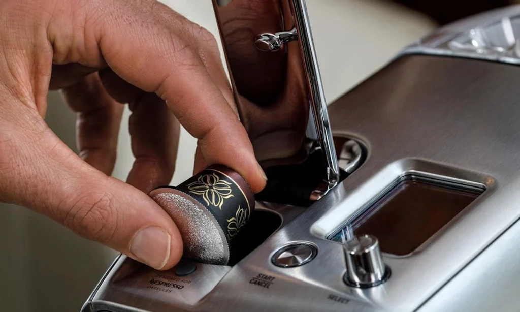 A person puts a Nespresso capsule into a coffee machine.