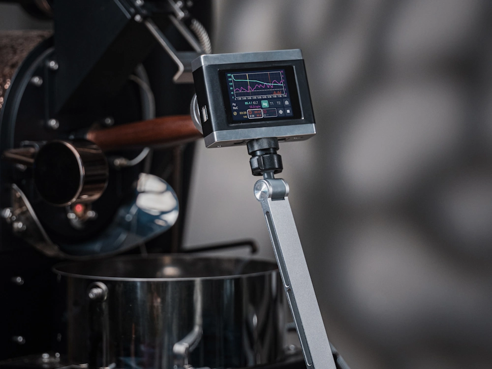 A DiFluid OmniFlux positioned in front of a coffee roaster.