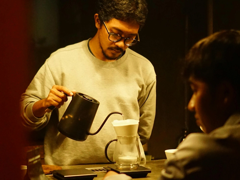 A barista prepares a pour over coffee for a customer.